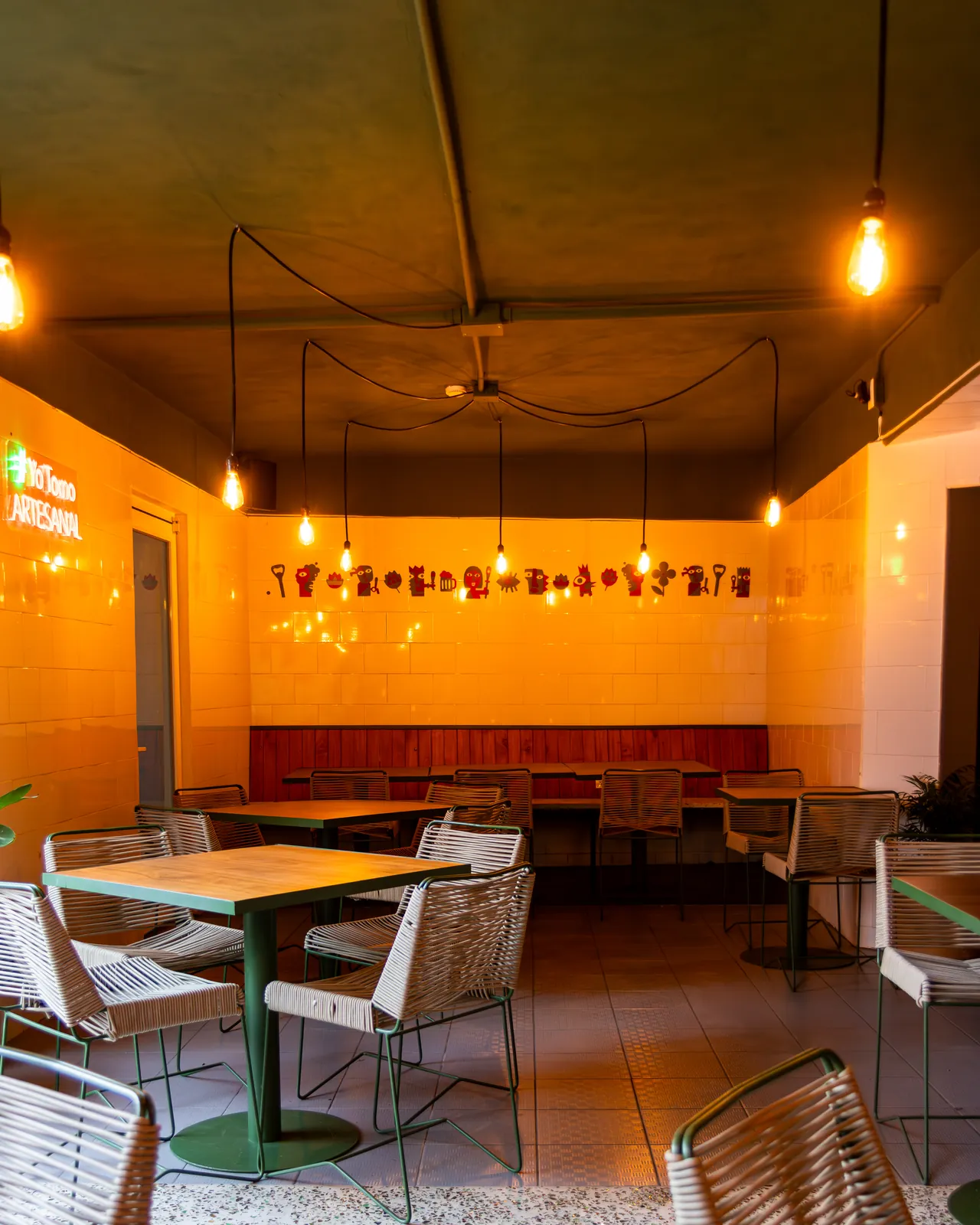 Interior de Irrestricta Draft House con mesas de madera e iluminación cálida