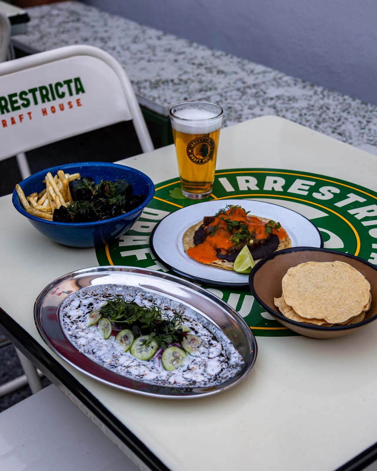 Mesa con tacos, mejillones, tostadas y cerveza artesanal